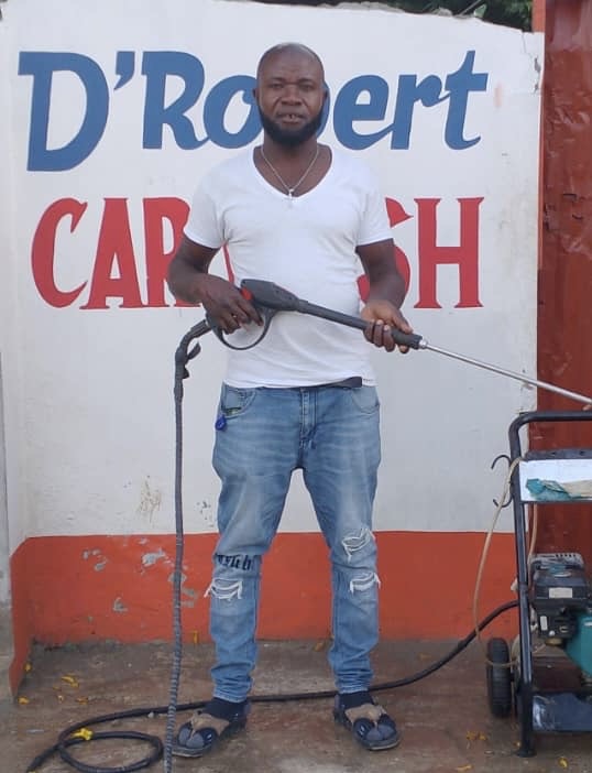 Robert at his car wash, holding a pressure-washer wand
