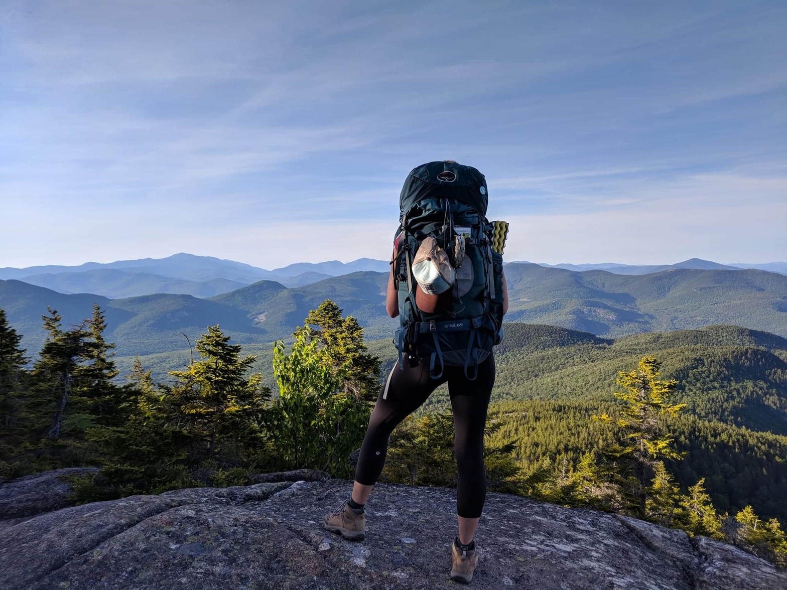 A hiker on a granite ledge overlooking the White Mountains