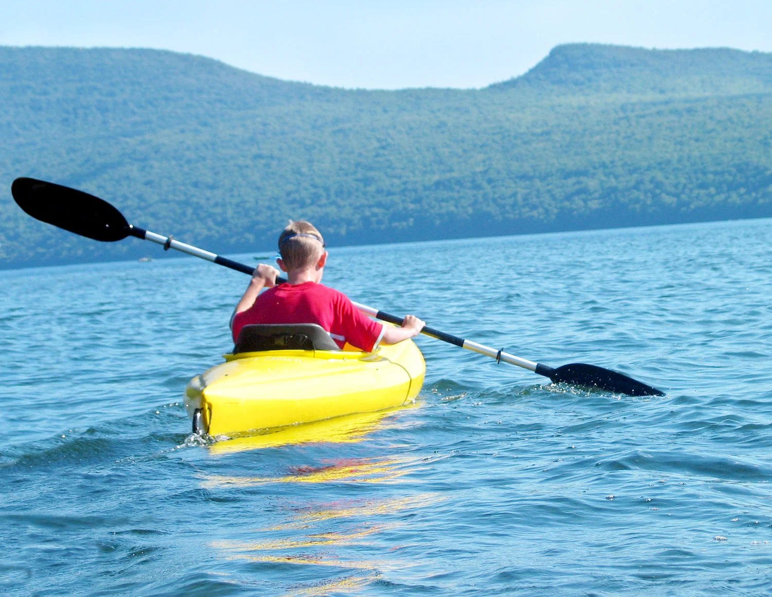 A kayaker paddling a yellow kayak on a New Hampshire lake