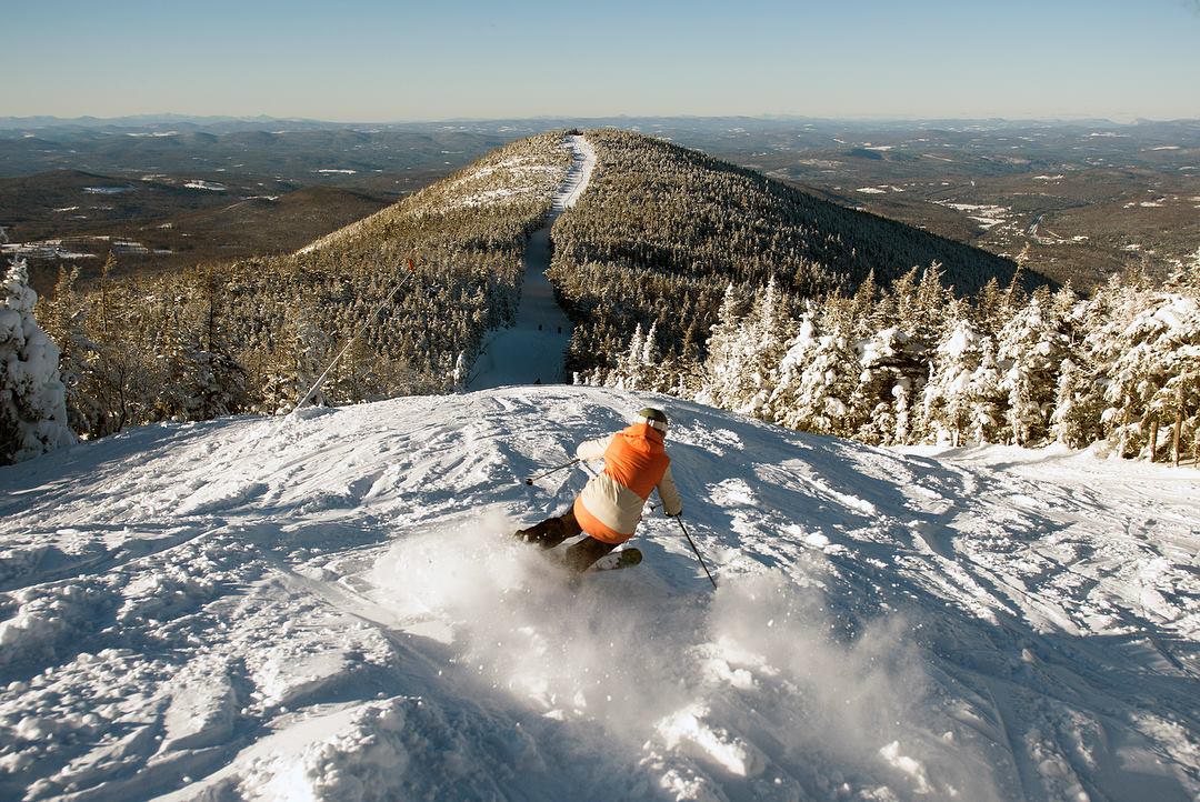 A skier on Cannon Mountain looking down a snow-covered ridge in the White Mountains