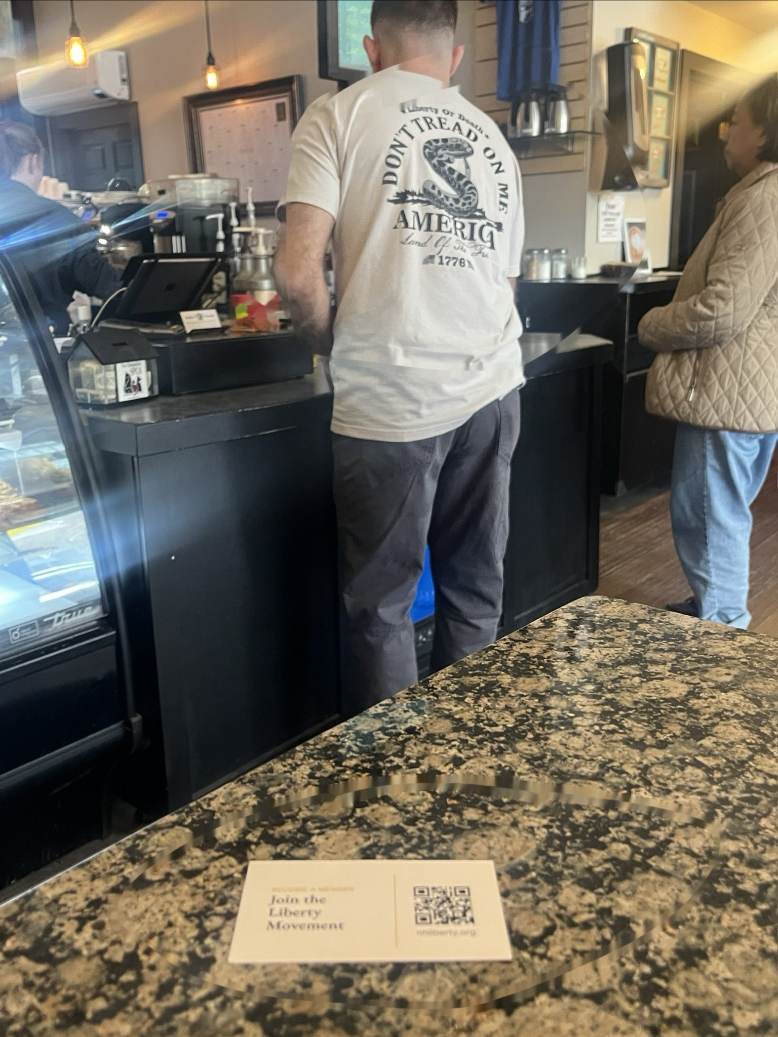 A Join the Liberty Movement card on a counter, and a Don’t Tread on Me shirt at the register