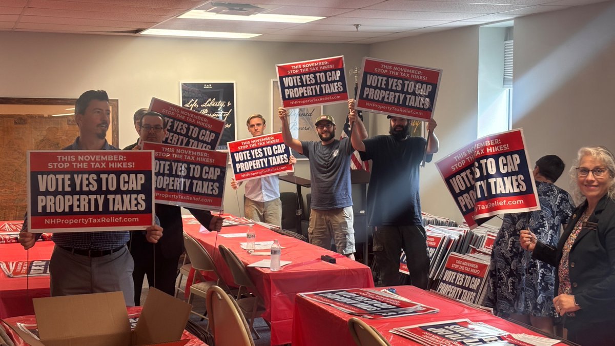 Volunteers holding signs that say Vote Yes to Cap Property Taxes